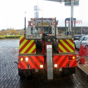 The back of the tow truck, reversing into position in the petrol station.