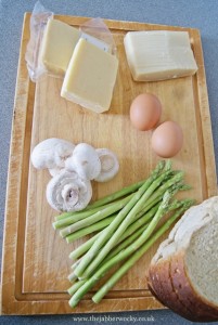 Asparagus, mushrooms, parmesan, eggs, cheddar and bread on a board