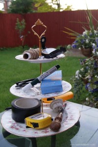 A selection of bits and bobs including duct tape, an old screwdriver, a pencil sharper, some string and a compass, looking epic on a cake stand.